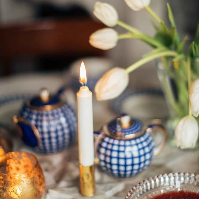 candle burning near flowers and tableware