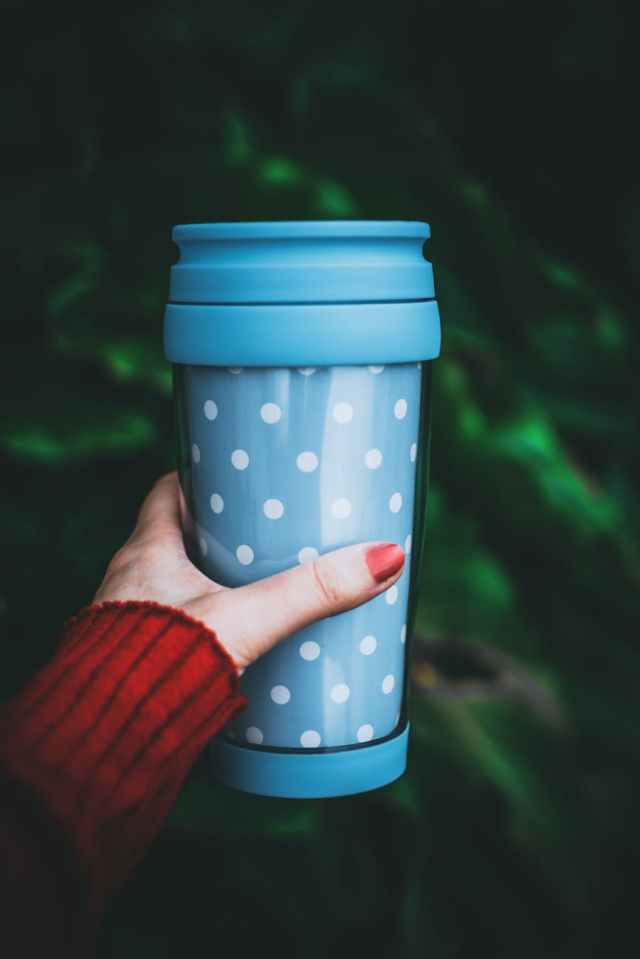 person holding teal and white polka dot tumbler